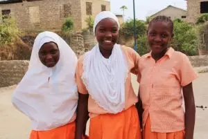 Drei junge schwarze Frauen stehen nebeneinander und lächeln fröhlich in die Kamera.