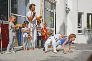 Fünf Kinder machen zusammen mit einem Trainer Capoeira.