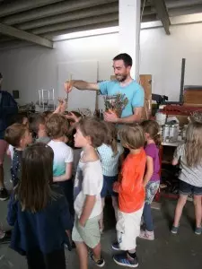 Ein Mann verteilt Pinsel an Kinder.