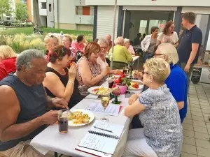 Eine Gruppe von Menschen sitzt an einem langen Tisch und isst zusammen.