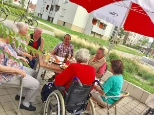 Eine Gruppe Senior*innen sitzt an einem Tisch auf einer Terrasse.