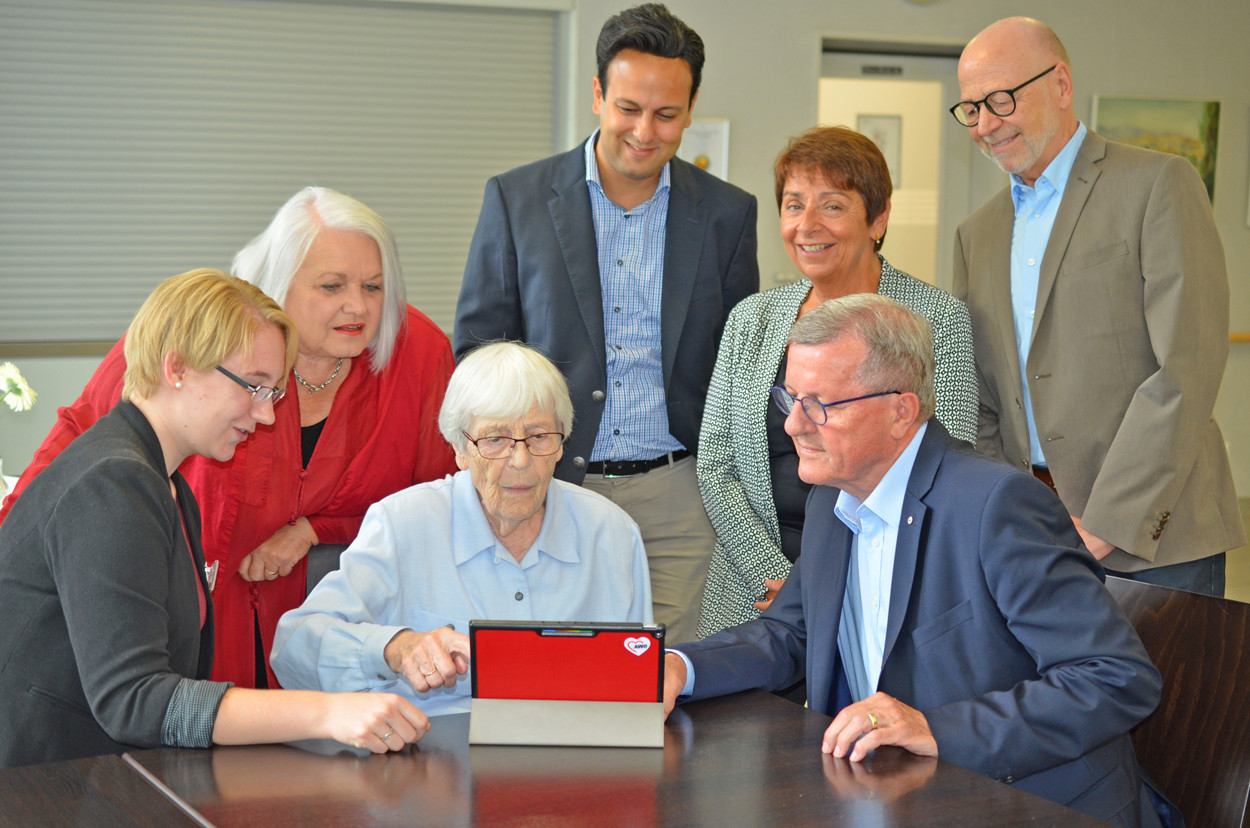 Eine Menschengruppe sitzt an einem Tisch und testet einen Tablet-PC.