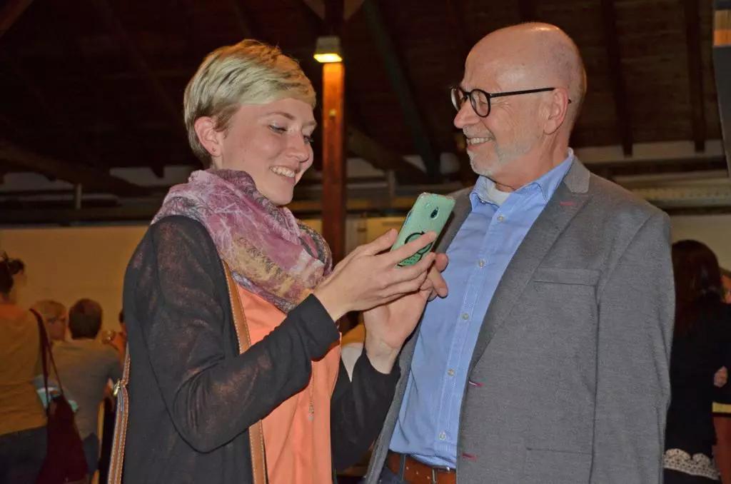 Ein Mann und eine junge Fraue schauen zusammen auf ein Handy.