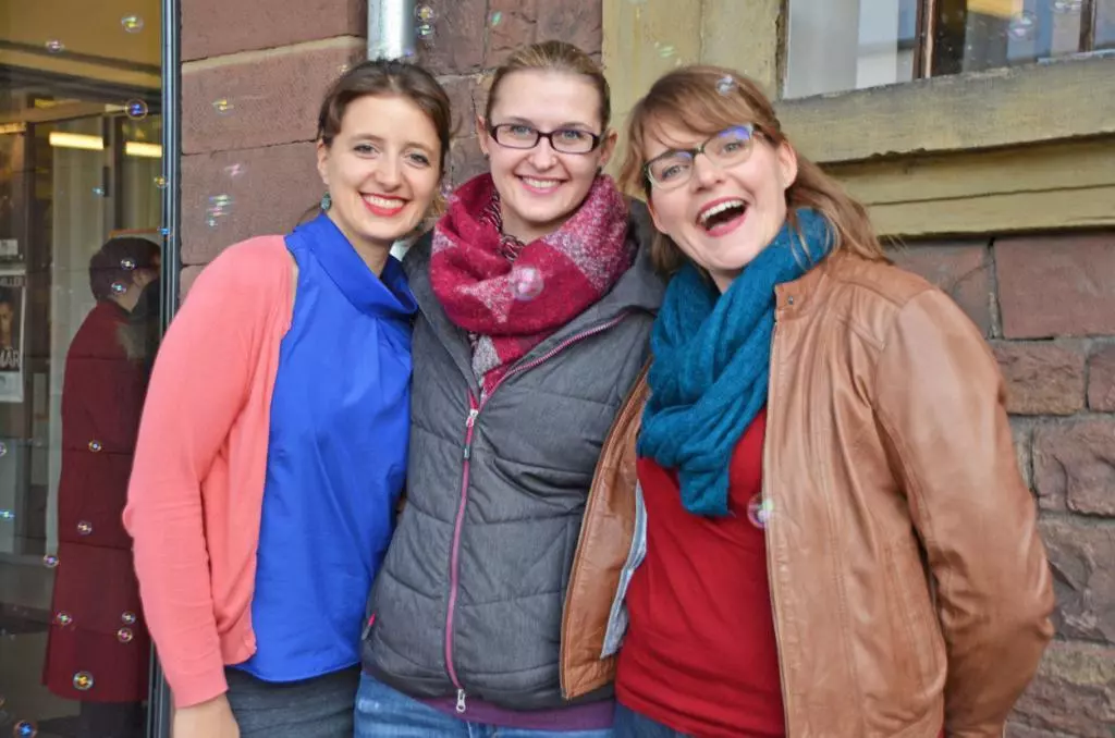 Drei junge Frauen lächeln in die Kamera.