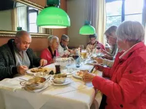 Menschen sitzen an einer Kaffeetafel und essen Kuchen.