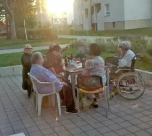 Eine Gruppe von Menschen sitzt an einem Tisch auf einer Terrasse.