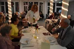 Eine Frau steht vor einem Tisch und schenkt Wein ein.