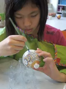 Ein Mädchen bemalt eine Glaskugel.