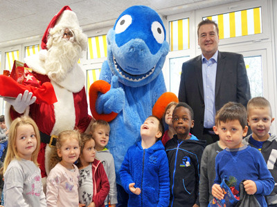 Eine Gruppe von Kindern steht mit einem Nikolaus und einer Hai-Figur im Halbkreis.