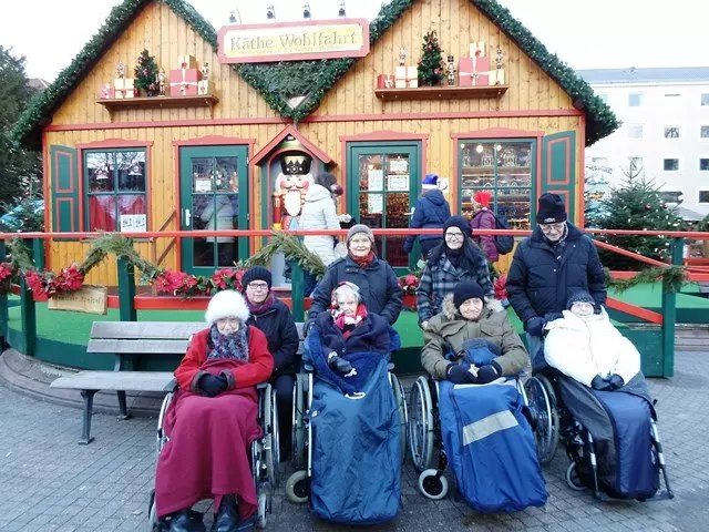 Eine Gruppe von Senior*innen sitzt in Rollstühlen auf dem Weihnachtsmarkt.