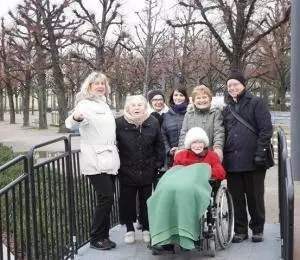 Eine Gruppe von Senioren steht vor dem Karlsruher Schloss im Park.