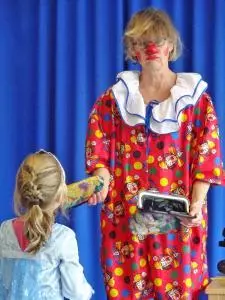 Eine Clownin gibt einem kleinen Mädchen die Hand.