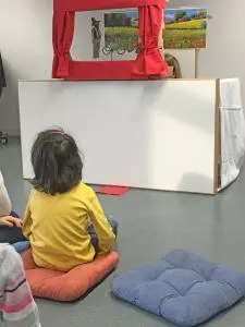 Ein Kind sitzt vor einem Puppentheater.