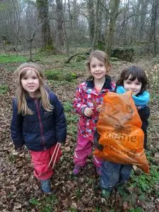 Kindergartenkinder stehen im Wald und lächeln.