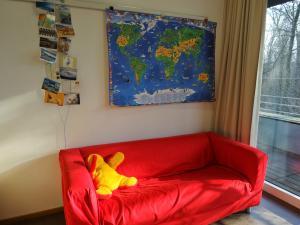 Eine rote Couch steht vor einer Wand an der eine Weltkarte hängt.