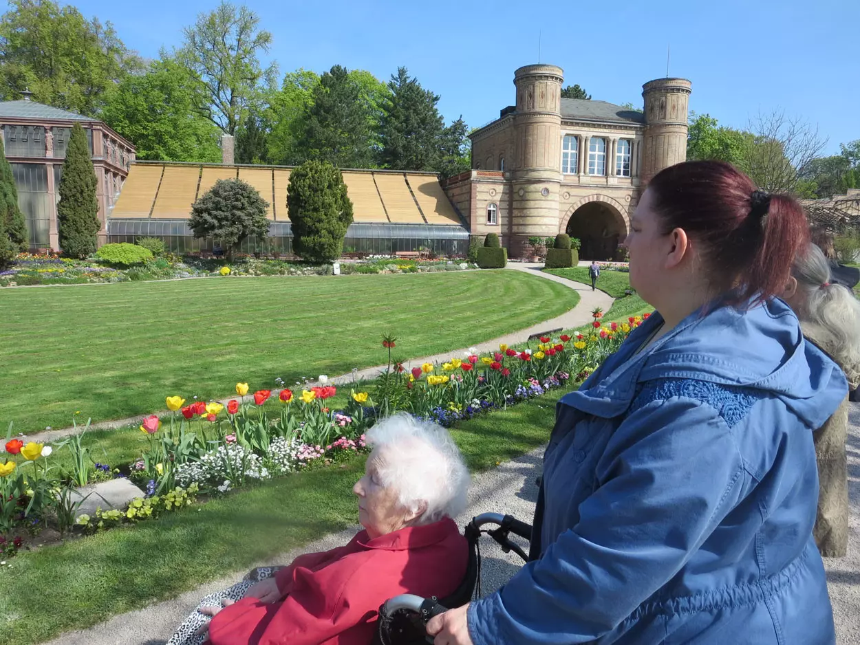 Karlsruher Schlosspark mit Blumen und Senioren.