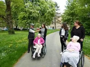 Ein Senior hält einer jungen Frau eine Blume hin.