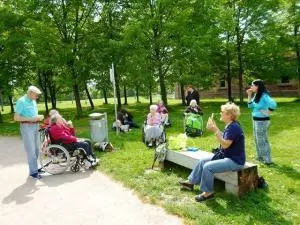 Senioren sitzen in ihren Rollstühlen und spazieren mit Betreuern durch den Otto-Dullenkopfpark.