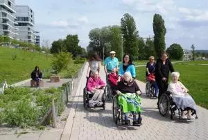 Senioren sitzen in ihren Rollstühlen und spazieren mit Betreuern durch den Otto-Dullenkopfpark.