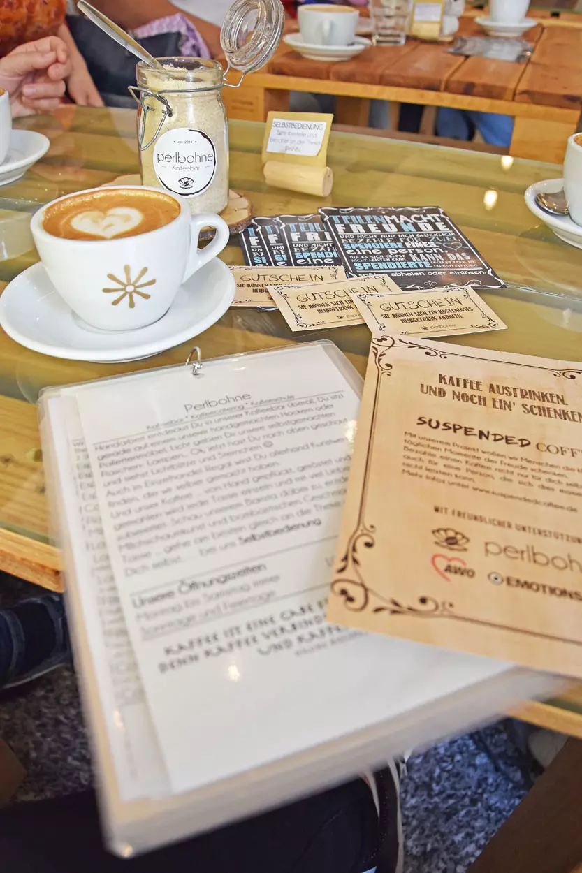 Auf einem Tisch steht eine Kaffeetasse danben liegen Gutscheine und Flyer.