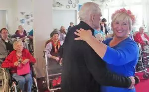 Ein Senior und eine Frau tanzen zusammen im Seniorenheim.