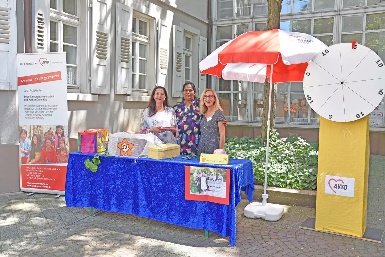 Drei Frauen stehen hinter einem Tisch an einem Infostand.