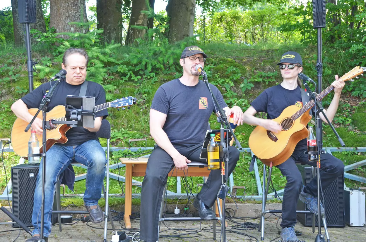 Drei Männer der Gruppe SKY Singers sitzen an ihren Instrumenten und geben ein Konzert.