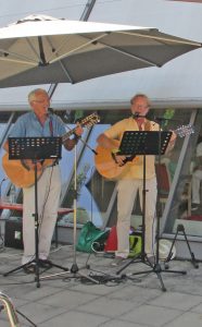 Zwei Männer stehen an Gitarren und singen.