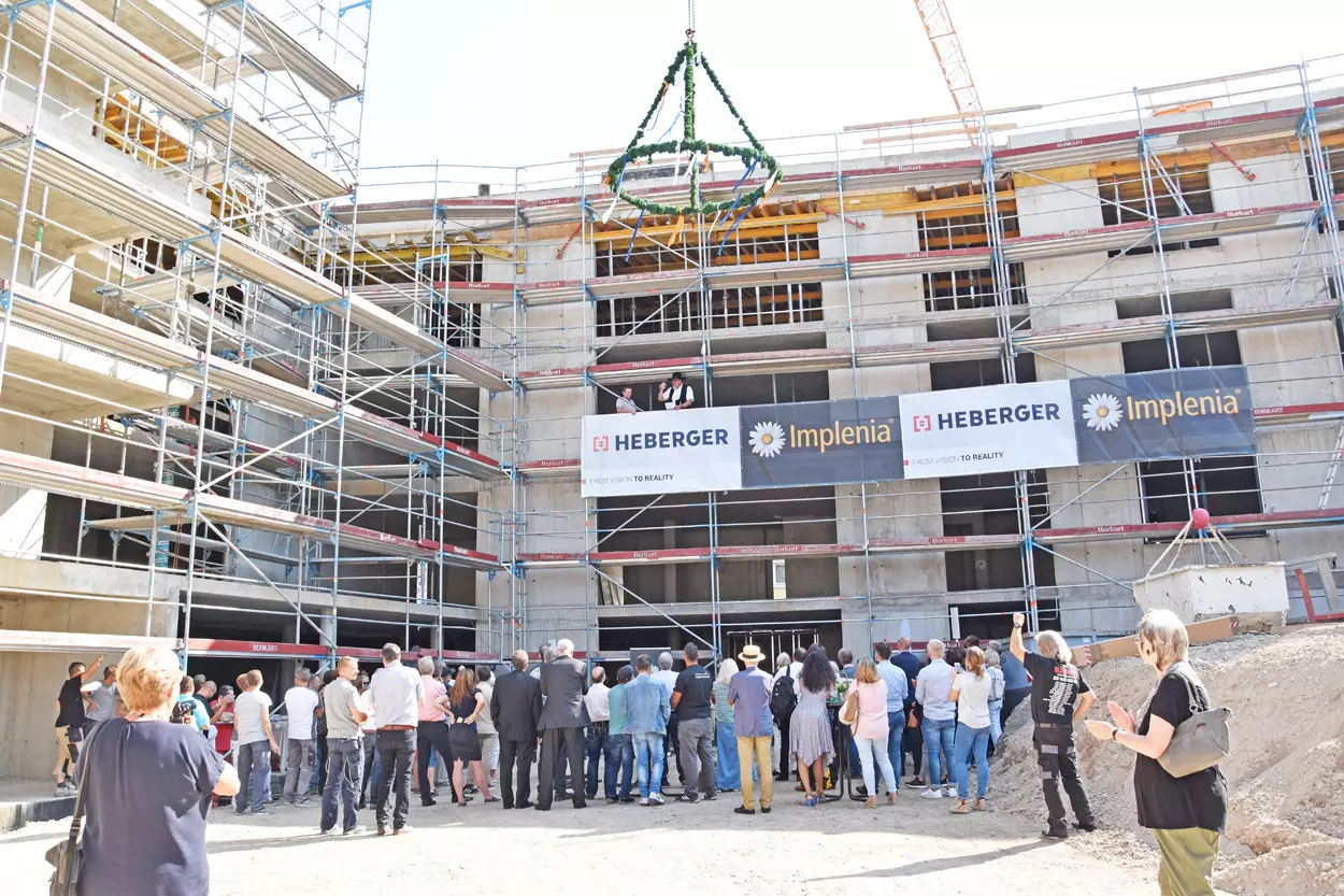 Eine Gruppe von Menschen steht auf einer Baustelle und feiert ein Richtfest.