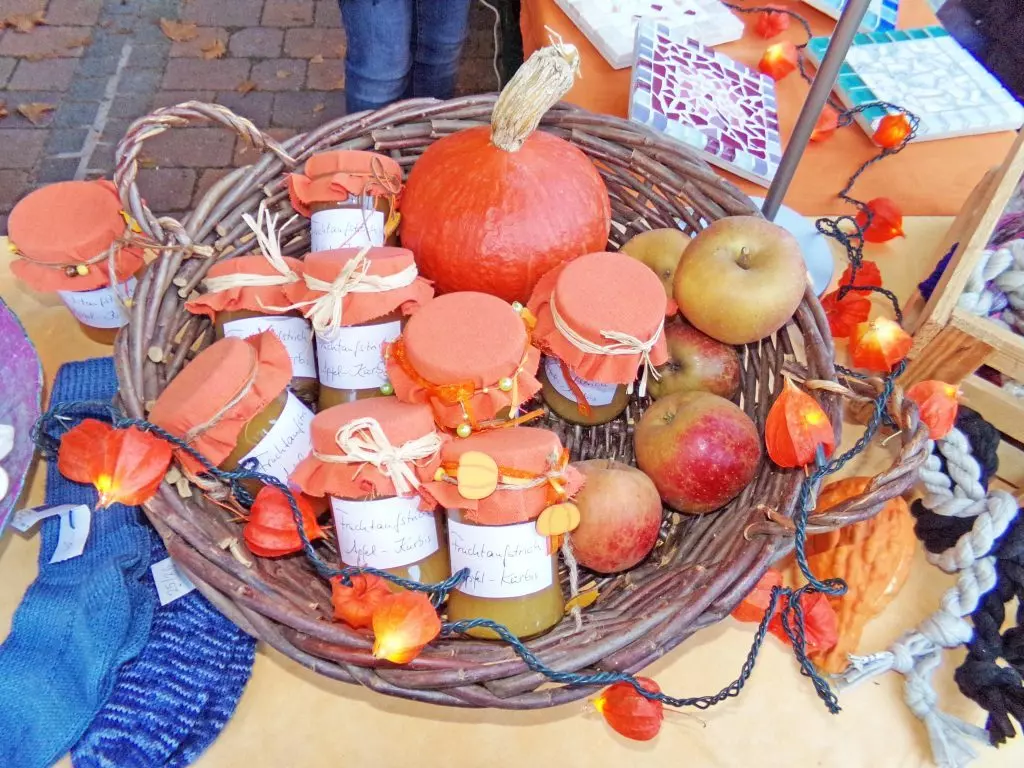 Ein Korb mit Kürbis und Marmeladengläsern.