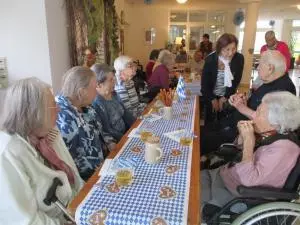 Menschen sitzen an einem langen Tisch und trinken Bier.