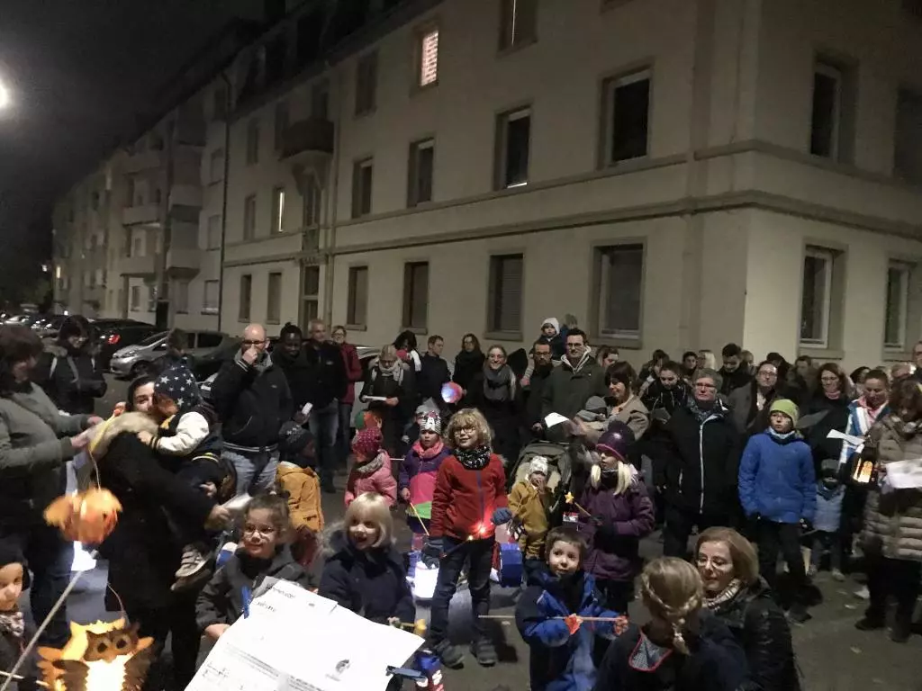 Menschen mit Laternen stehen nachts auf einer Straße.