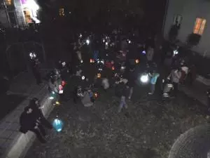 Menschen mit Laternen laufen nachts über eine Straße.