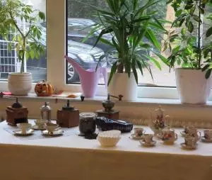 Kaffeekannen und Tassen stehen zusammen mit Kaffeemühlen auf einem gedeckten Tisch.