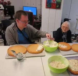 Ein junge Mann und eine ältere Damen backen zusammen Kuchen.
