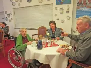 Drei Menschen sitzen an einem Tisch und essen eine Martinsgans.