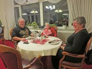 Drei Menschen sitzen an einem Tisch und essen eine Martinsgans.