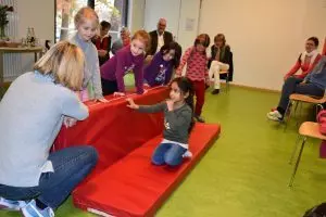 Kinder turnen auf einer Sportmatte.