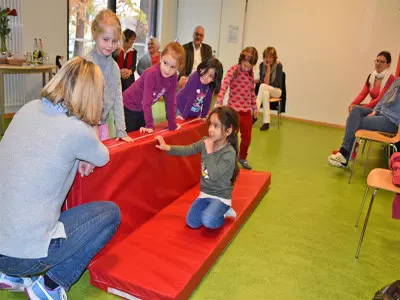 Kinder turnen auf einer Sportmatte.