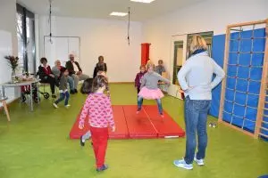 Kinder turnen auf einer Sportmatte.