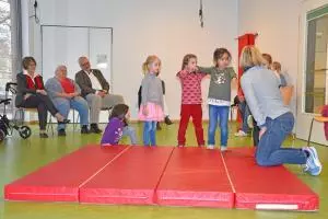 Kinder turnen auf einer Sportmatte.