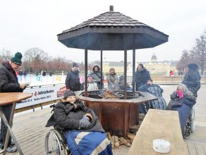 Menschen stehen an einem Tisch im Freien und trinken etwas.