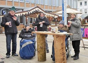 Menschen stehen an einem Tisch im Freien und trinken etwas.