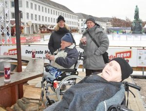 Menschen stehen an einem Tisch im Freien und trinken etwas.