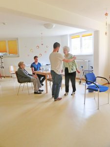 Ein Student und eine Seniorin machen zusammen Sportübungen.