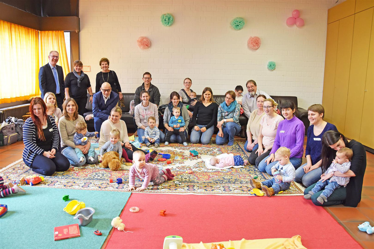 Eine Gruppe von Müttern sitzt auf einem Teppich und spielt mit ihren Babys.