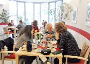 Frauen und Männer sitzen an einem Tisch und schauen in die Kamera