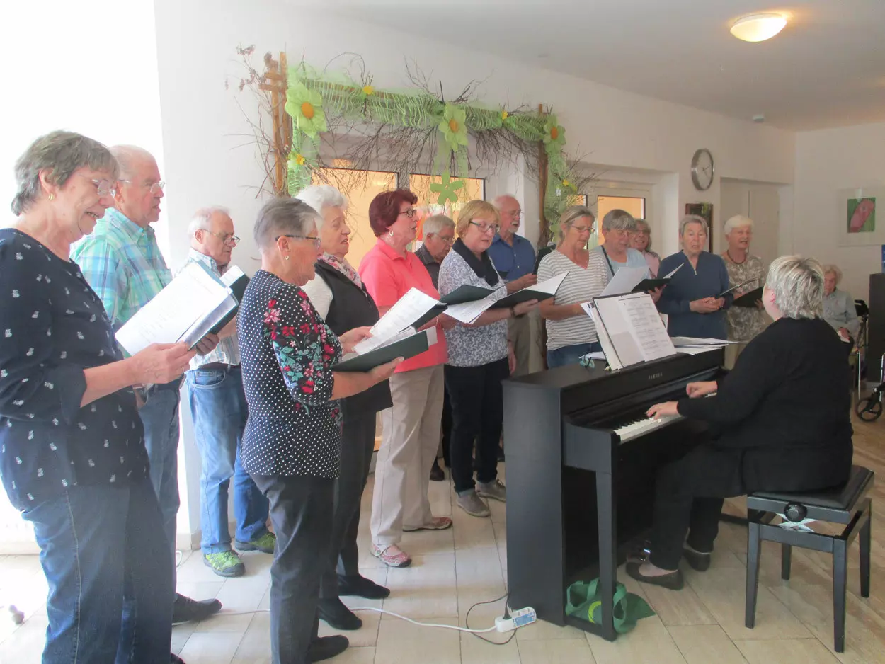 Männer und Frauen stehen in Reihen und singen.