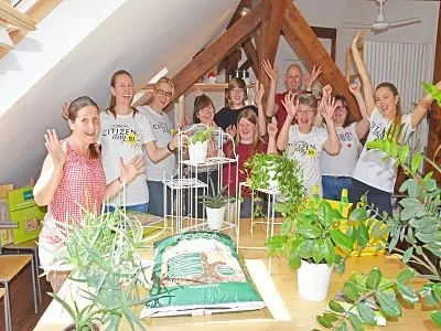 Gruppenbild von Mitarbeiter*innen und Klientinnen der Durlacher Jugendhilfen sowie Mitarbeiterinnen von L'Oréal - sie heben die Hände und schauen direkt in die Kamera.
