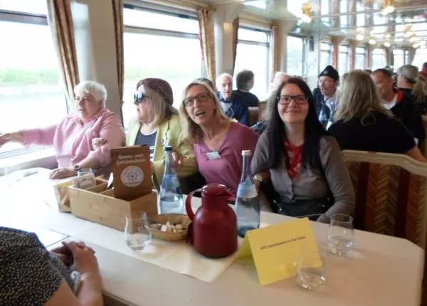 Vier Frauen sitzen auf einer Bank unter Deck auf dem Schiff und schunkeln